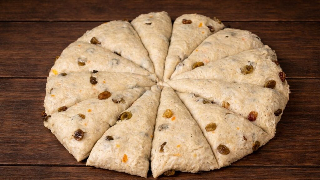 Soft and fluffy Hot Cross Buns – dough on a lightly floured work surface divided into 12 equal portions, ready to be shaped into smooth buns.