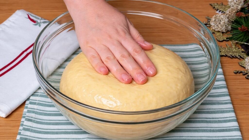 Smooth, kneaded dough resting in a lightly oiled glass bowl, covered and ready to rise for about one hour until soft and puffy.