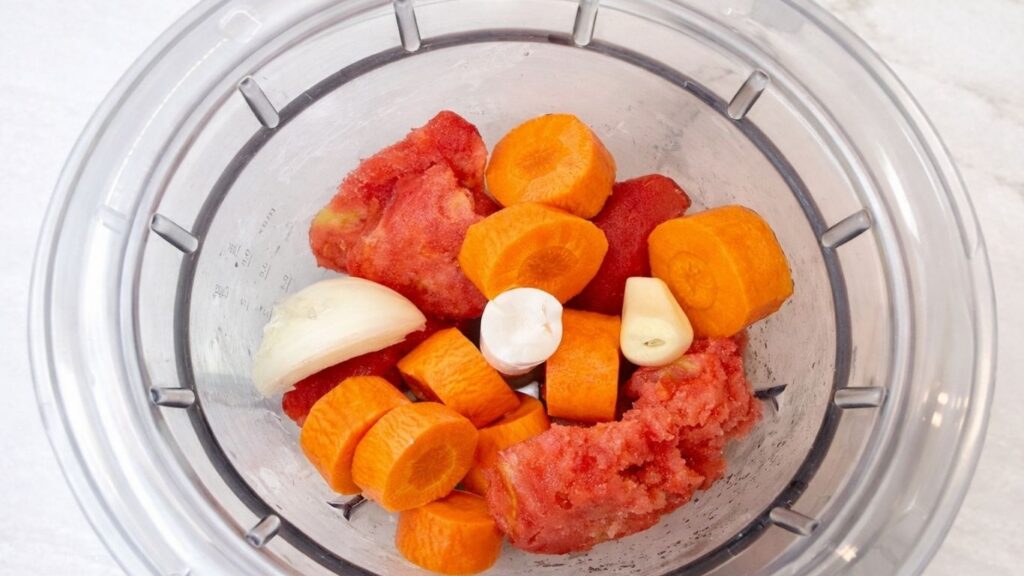 vegetables in a hand blender including onion, carrot, and garlic ready to be blended for stuffed cabbage rolls (sarma) filling mixture