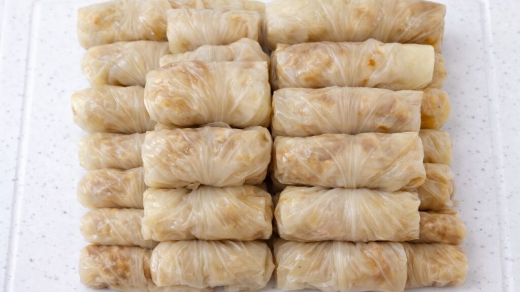 A pile of neatly rolled sarma, stuffed sour cabbage rolls filled with meat and rice, ready to be arranged in the pot for cooking