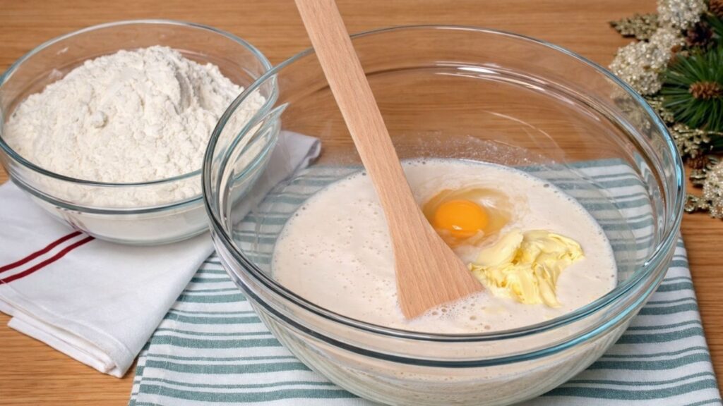 Glass bowl with activated, risen yeast mixed with all the other ingredients, ready for the flour to be added and the dough to be formed.