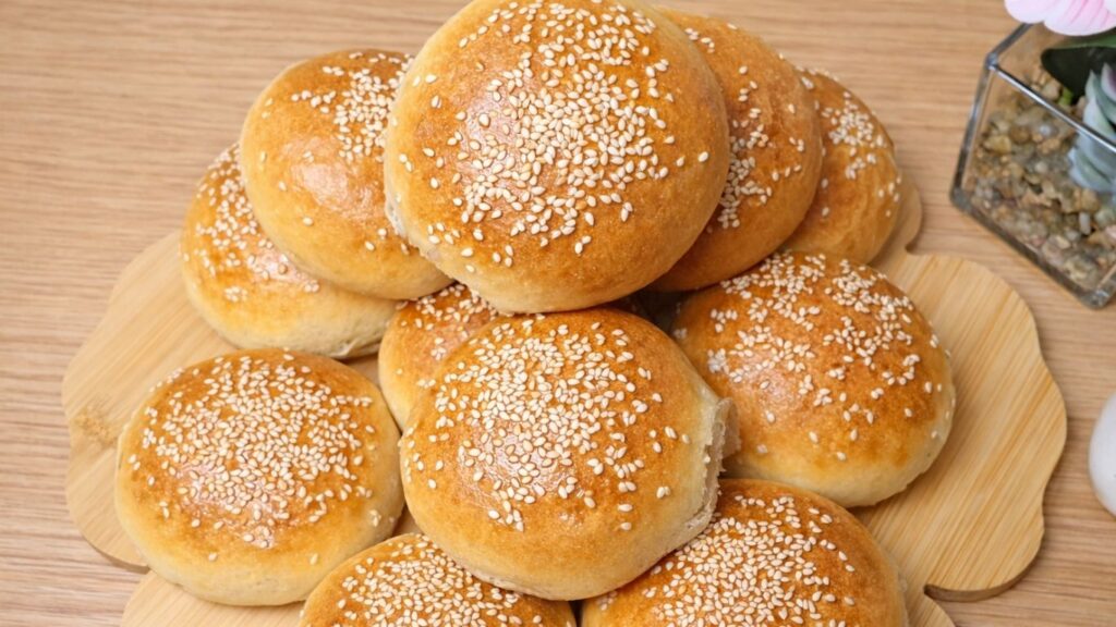 Stacked burger buns arranged on a wooden board, beautifully golden, soft and fluffy, ready to serve and enjoy