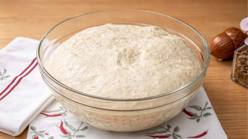 Risen dough in a glass bowl, doubled in size with a soft and airy texture, ready to be shaped and prepared for baking