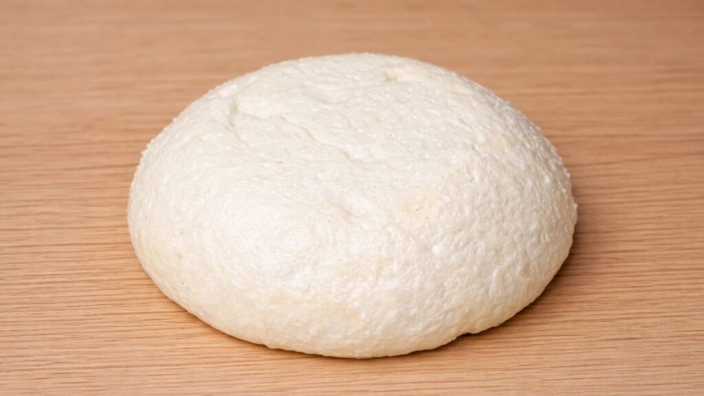 burger dough turned out of the bowl onto a clean work surface, soft and smooth, ready for kneading and shaping into burger buns
