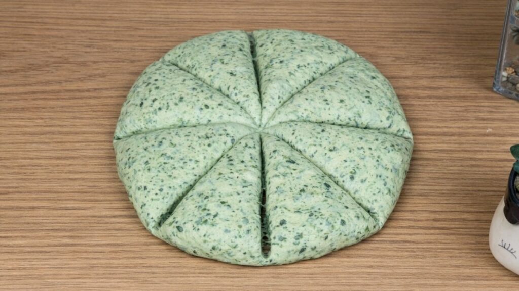 Green dough on a clean work surface divided into eight equal portions, smooth and soft pieces ready to be shaped into burger buns, natural baking preparation scene