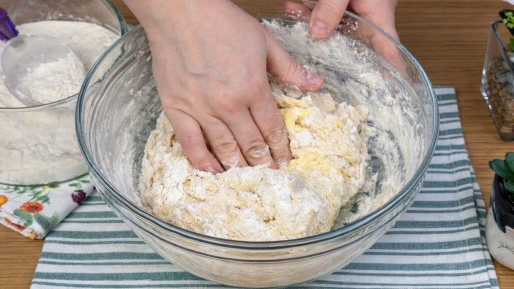 Hand kneading soft dough in a glass bowl for natural colored burger buns, smooth and elastic texture forming, clean and natural baking preparation scene
