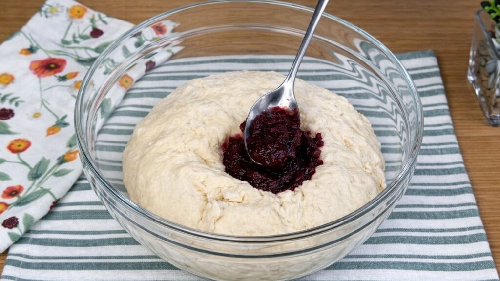 Glass bowl with the third portion of dough as blended beetroot is being added to color it naturally pink, close-up clean baking preparation scene