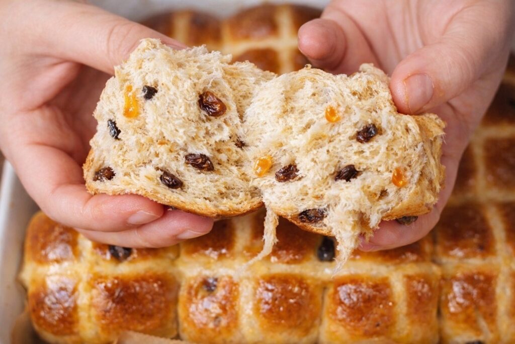Soft and fluffy hot cross bun opened in half showing light, airy texture inside