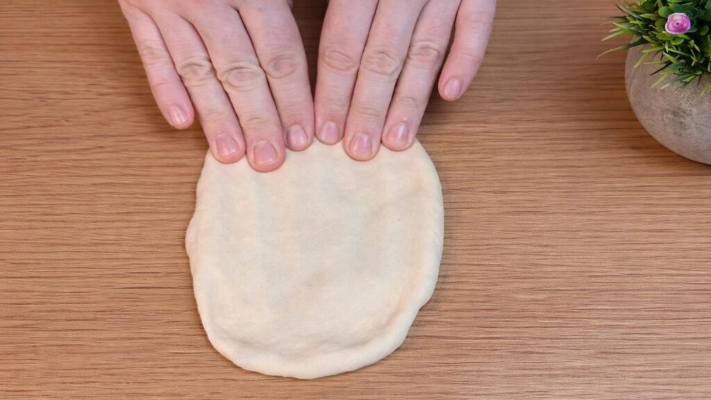 Shaping the dough by hand into hot dog buns before the second rise.