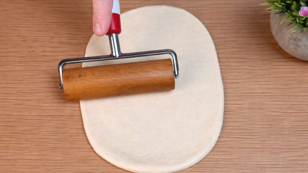 Using a small rolling pin to shape the dough evenly for homemade hot dog buns.
