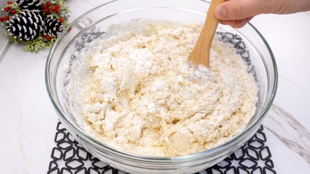mixing all ingredients with a wooden spoon to make soft dough for homemade dinner rolls