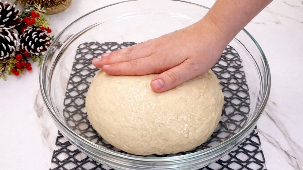 coating the dough with oil by hand in a bowl for homemade dinner rolls
