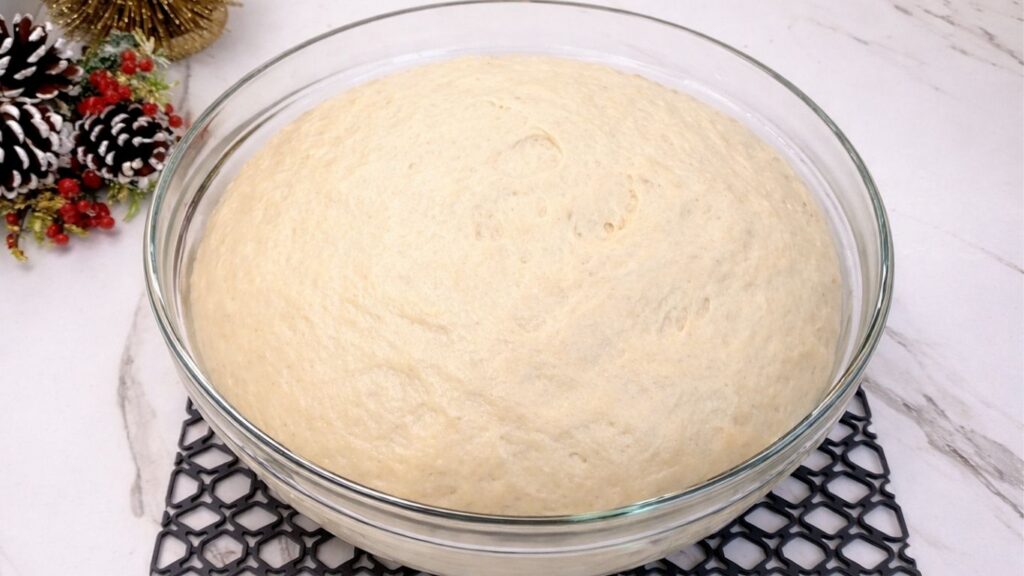 dough doubled in size in the bowl after rising for soft homemade dinner rolls
