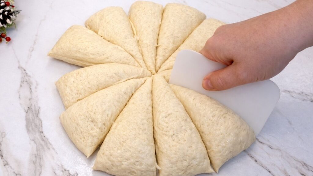 dough on a clean work surface divided into 12 equal pieces for homemade dinner rolls