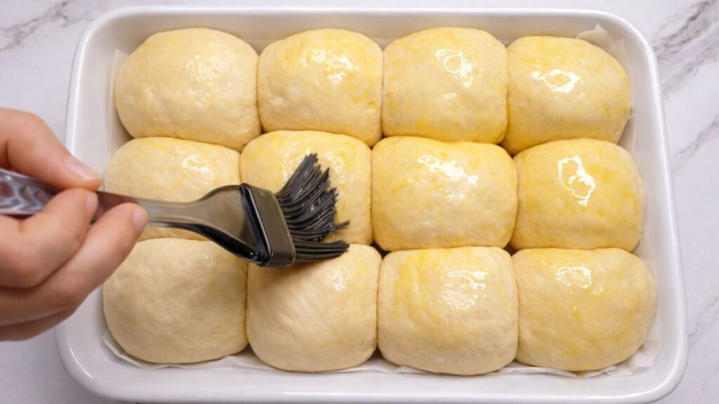 brushing dinner rolls with egg and milk using a pastry brush