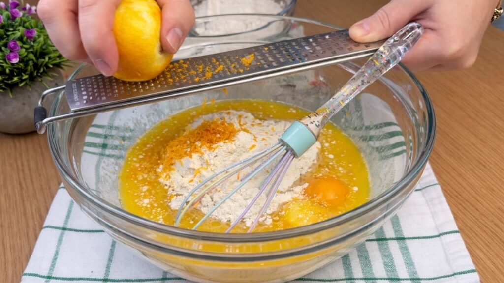 grating fresh lemon zest into the dough mixture for blueberry lemon rolls
