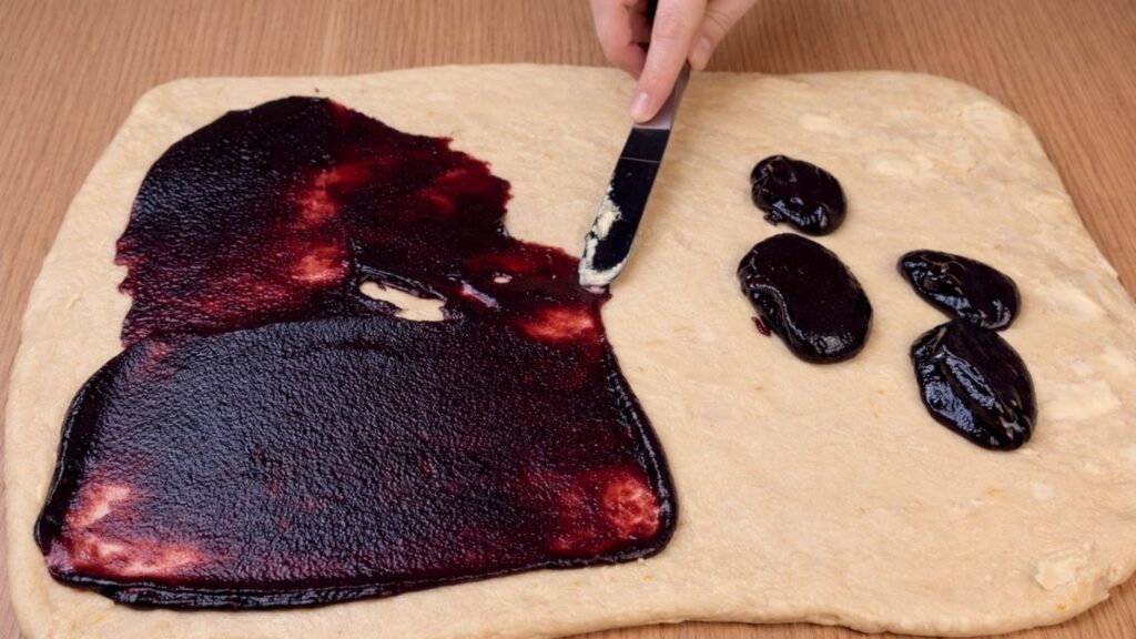 rolled dough spread evenly with blueberry jam for blueberry lemon rolls