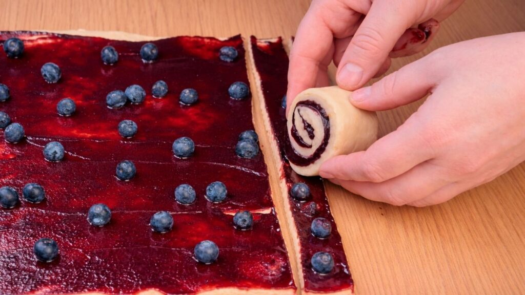rolling the dough strips into spiral blueberry lemon rolls