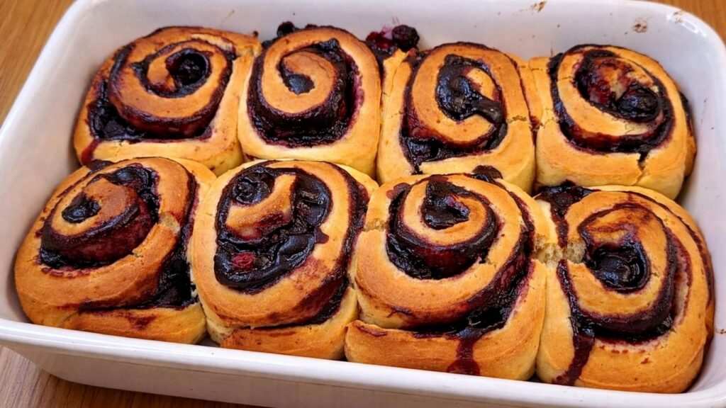 freshly baked blueberry lemon rolls in a baking pan with golden brown tops