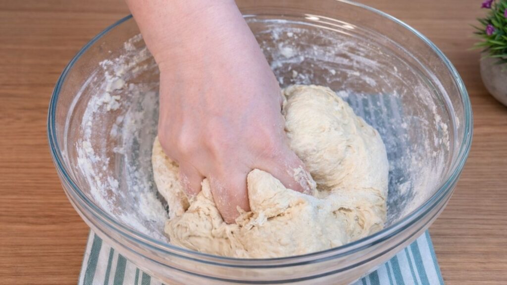 Mixing the dough by hand in a bowl while preparing homemade hot dog buns.