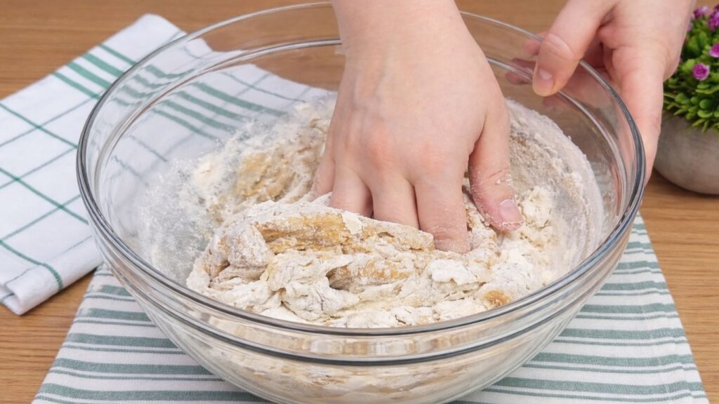 Mixing the apple cinnamon roll dough by hand in a bowl with all the ingredients combined.