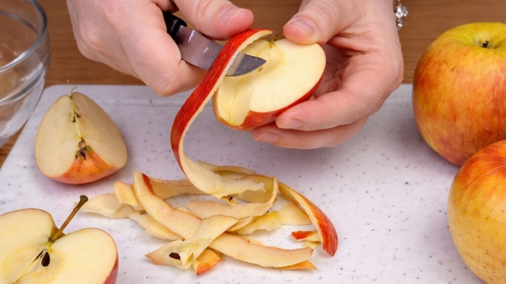 Peeling fresh apples to prepare the filling for homemade apple cinnamon rolls.