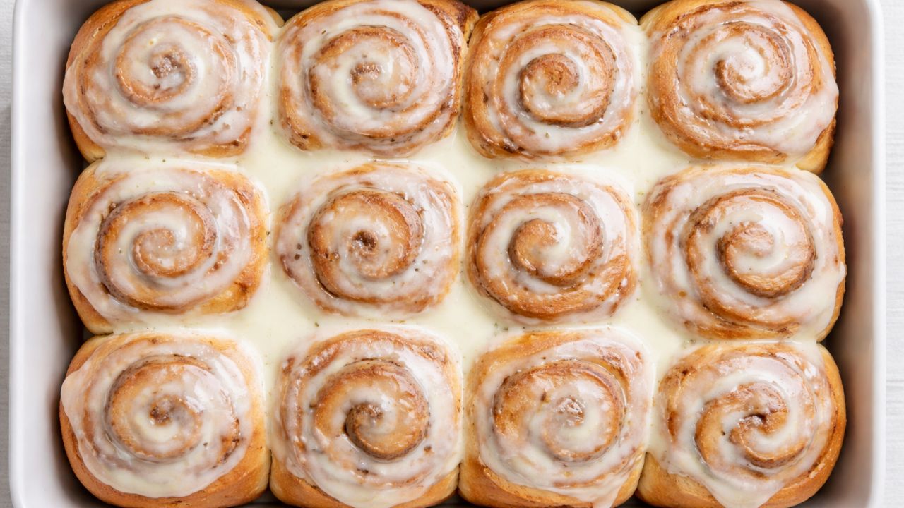 homemade cinnamon rolls in a baking pan topped with cream cheese glaze