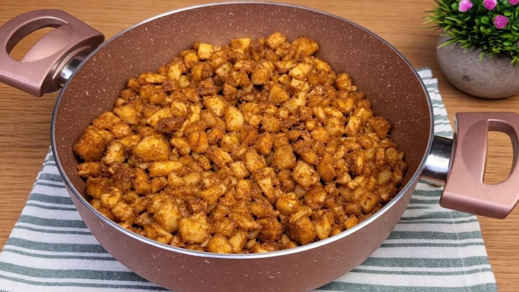 Diced apples in a saucepan mixed with brown sugar and cinnamon to make the apple cinnamon roll filling.