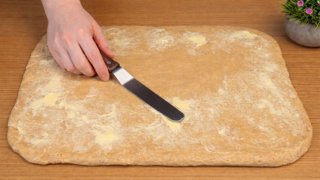 Apple cinnamon roll dough spread with a thin layer of butter before adding the apple filling.