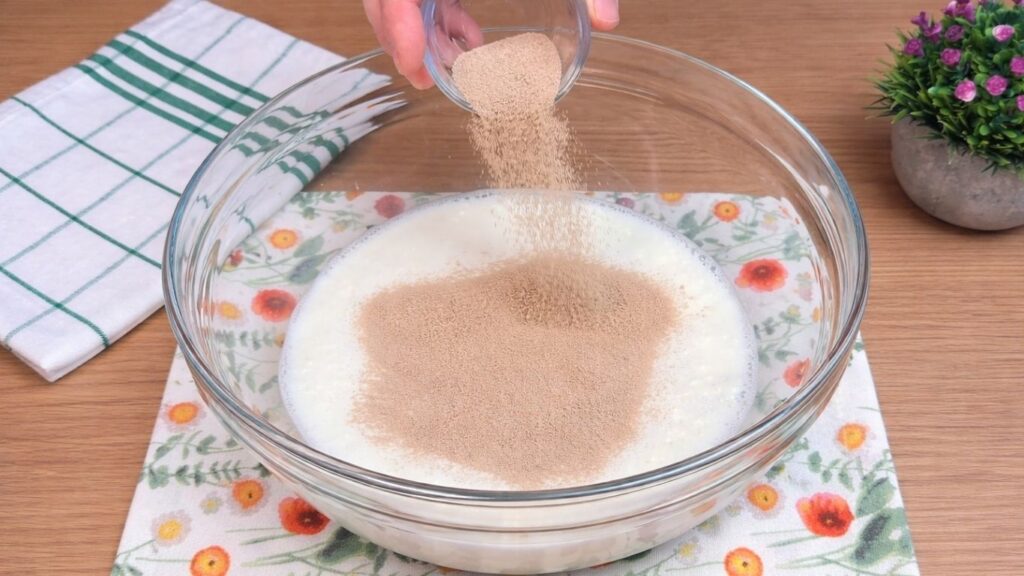 adding active dry yeast to warm milk mixture for homemade cinnamon rolls