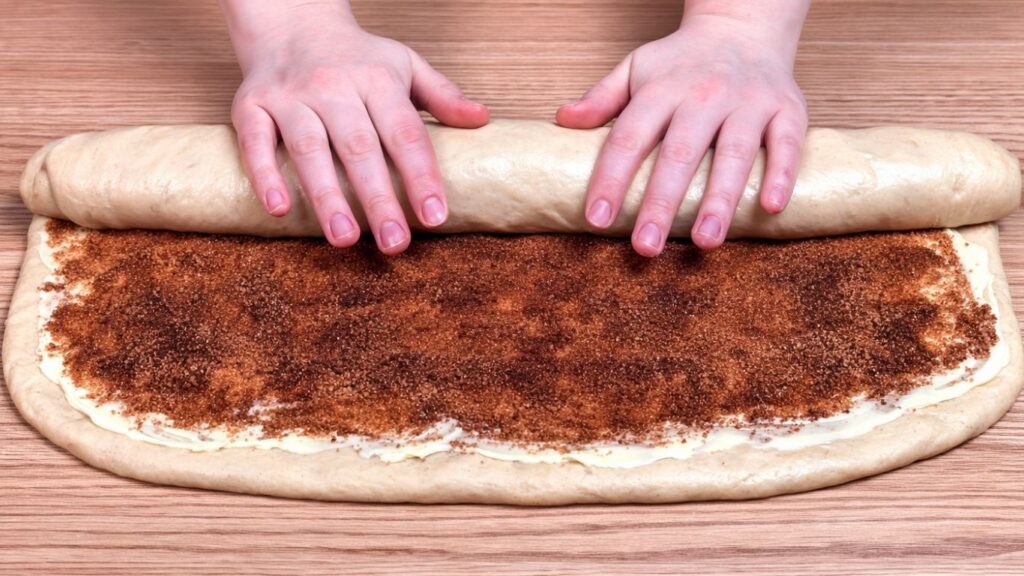 rolling filled dough into a tight log for homemade cinnamon rolls