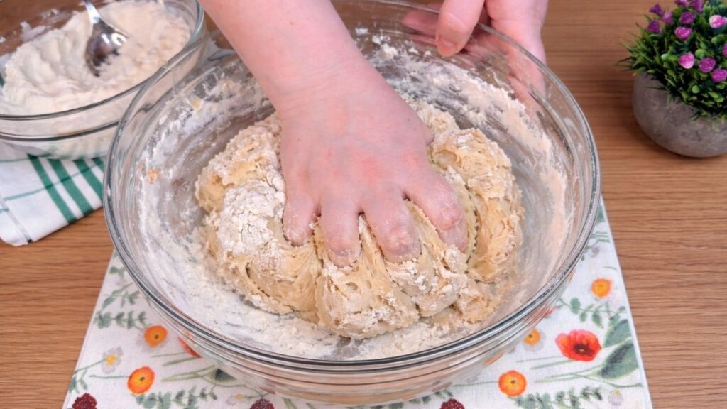 mixing dough by hand in a bowl for homemade cinnamon rolls