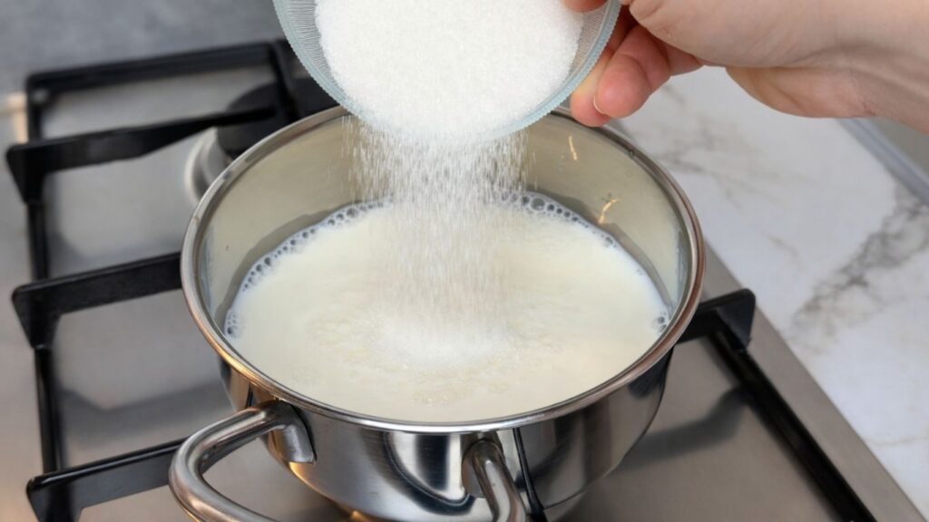 milk in saucepan on stove for lemon cream filling adding sugar to milk in saucepan