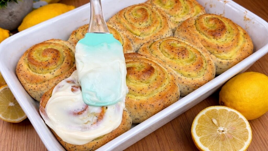 spreading cream cheese frosting on warm rolls