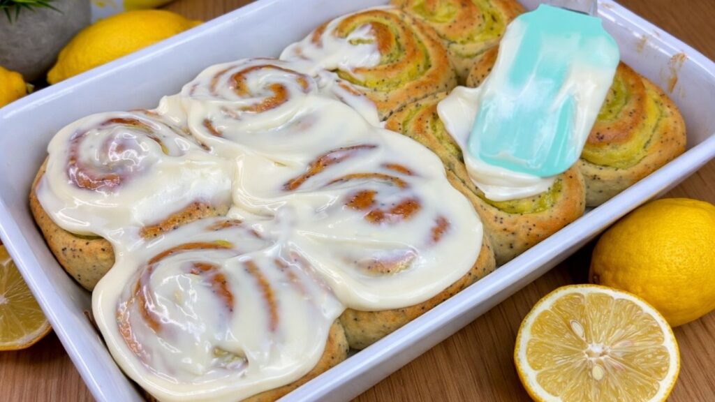 spreading cream cheese frosting on warm rolls
