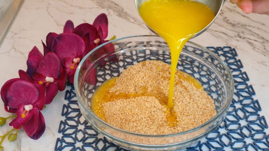 Pouring melted butter into crushed cookies for no bake cake crust