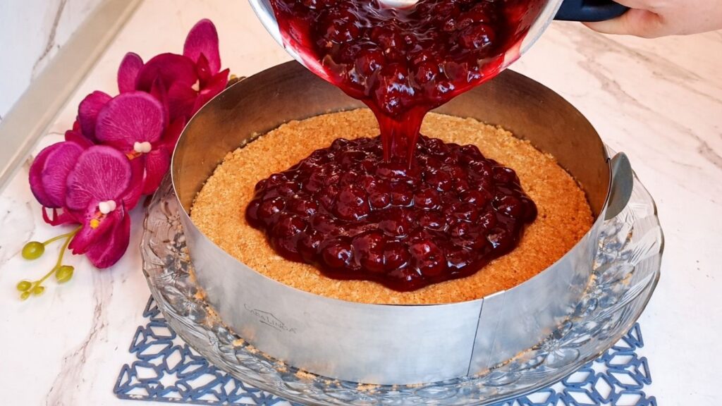 Pouring cooked cherry layer over cookie crust in cake pan
