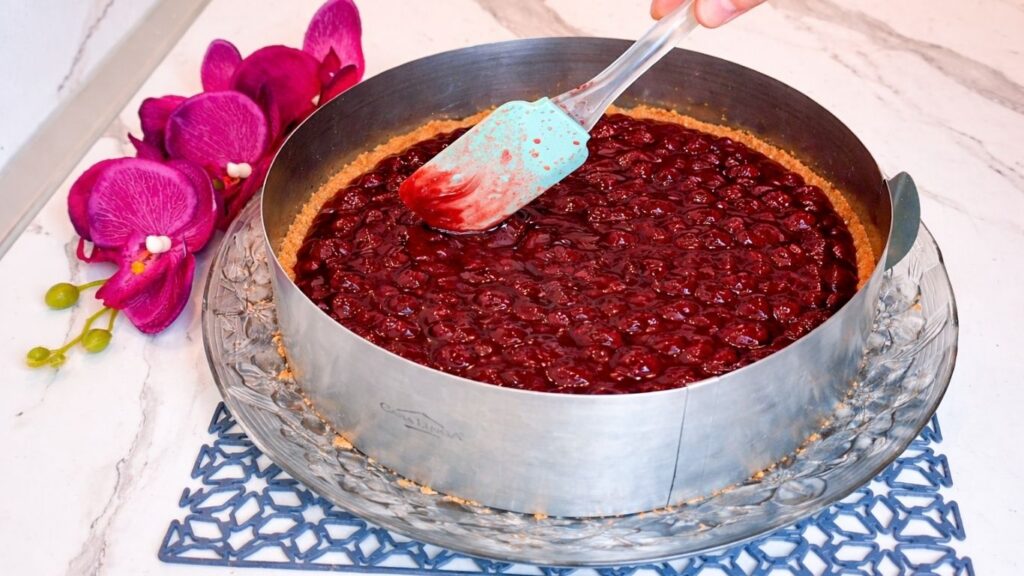 Spreading cherry layer evenly over cookie crust in cake pan
