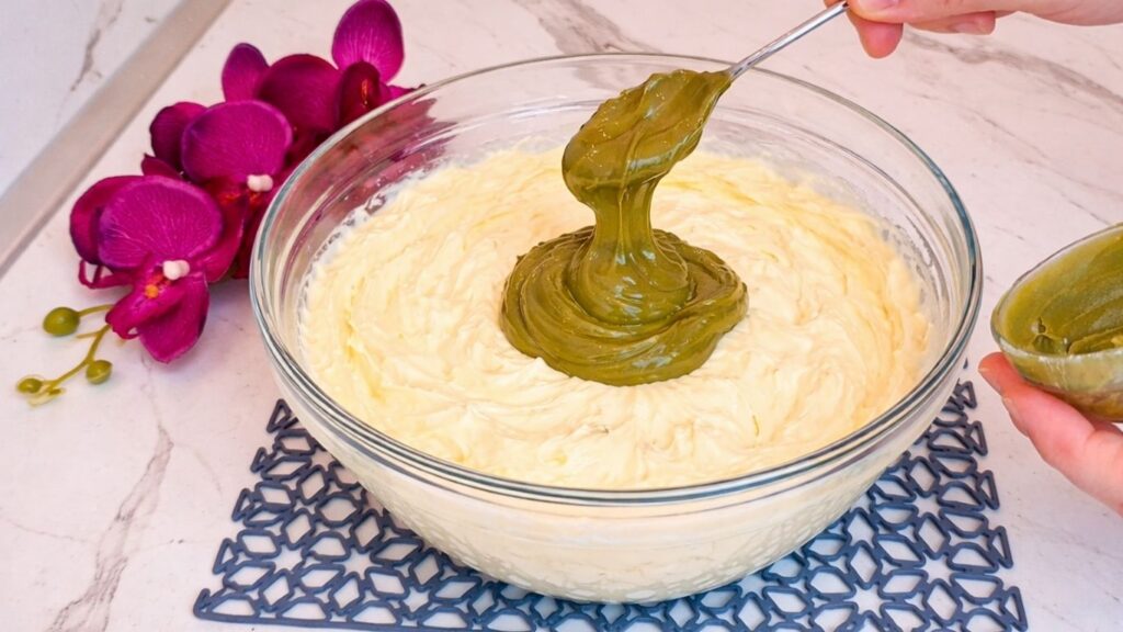 Adding pistachio paste to whipped vanilla cream for pistachio filling