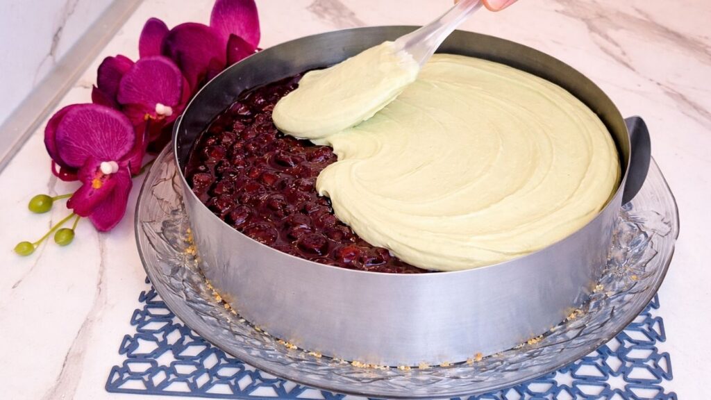 Spreading pistachio cream over cherry layer in no bake pistachio cake