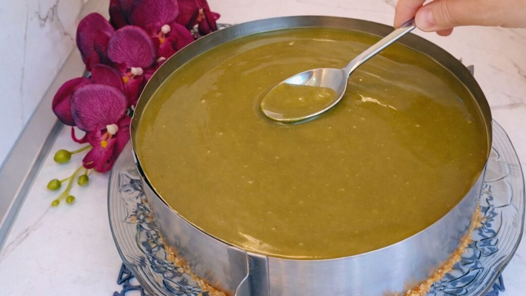 Spreading pistachio ganache evenly over the no bake pistachio cake