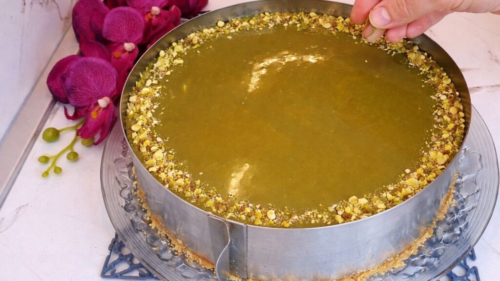 Decorating the edges of the no bake pistachio cake with chopped pistachios