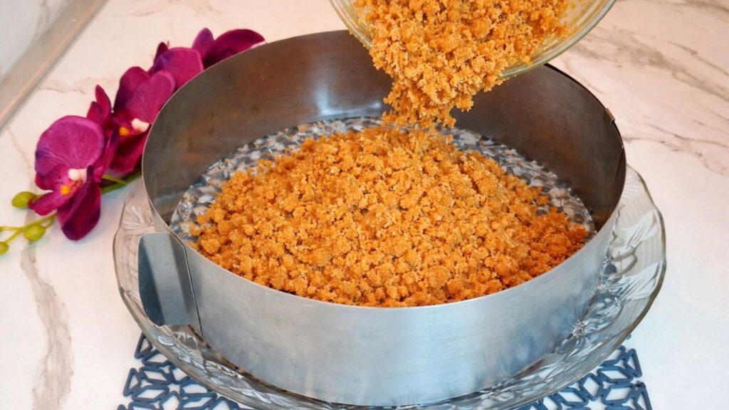 Pouring cookie crust mixture into cake pan for no bake pistachio cake