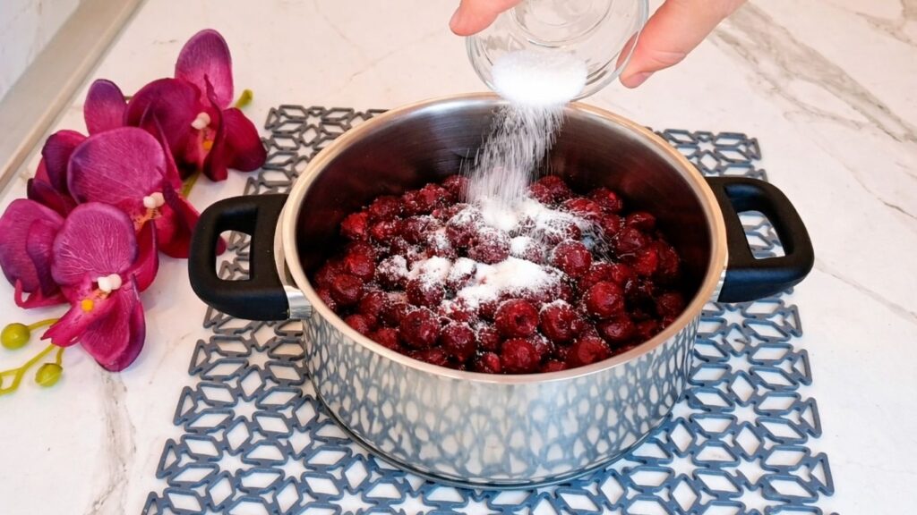 Adding sugar to cherries in saucepan for cherry layer