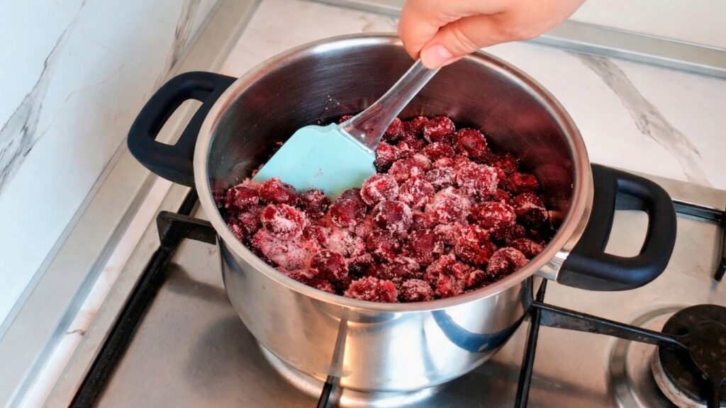 Cooking cherries with sugar in saucepan for cherry layer