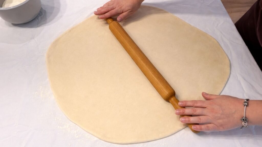 rolling potato borek dough with a rolling pin on a floured surface