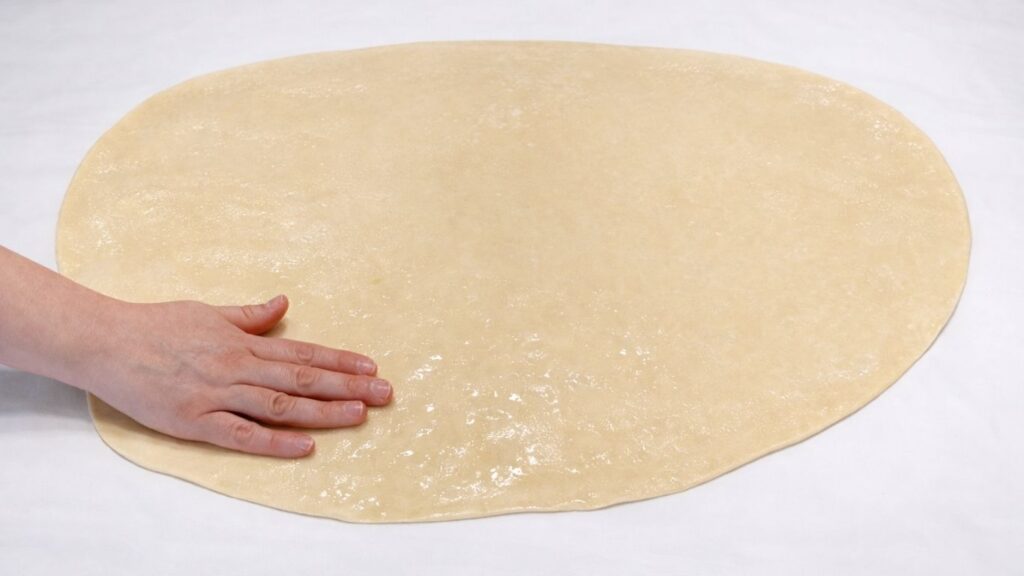 brushing oil over stretched potato borek dough before hand stretching