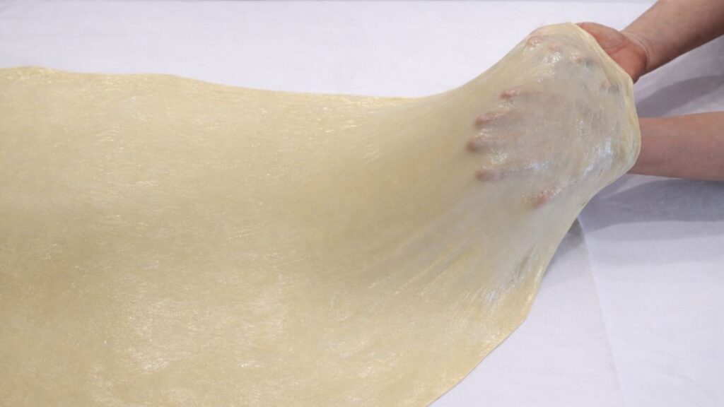 stretching potato borek dough by hand into a thin sheet