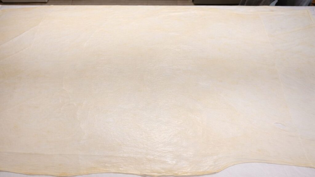 thinly stretched potato borek dough spread across the table ready for filling