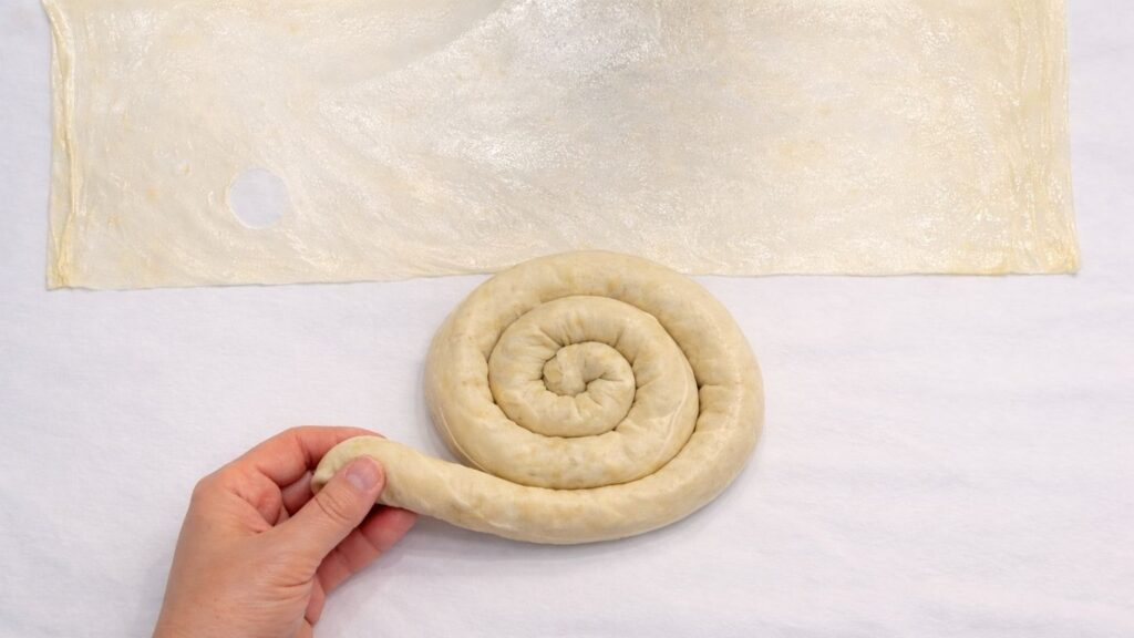 rolling filled potato borek dough into a spiral shape